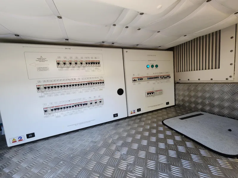 Slide: The Image of Electrical control panels inside a 2022 Pershing 6X yacht, featuring circuit breakers and metallic flooring. - 34