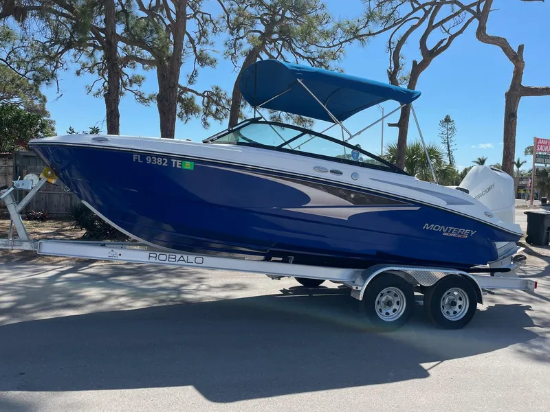 The Image of 2022 Monterey M-205 boat on trailer with blue canopy, parked outdoors. - 0