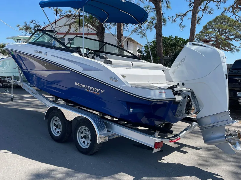 Slide: The Image of 2022 Monterey M-205 boat on trailer, blue and white design, parked outdoors. - 1