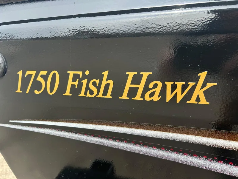 Slide: The Image of 2004 Crestliner 1750 FishHawk SC boat model name in gold lettering on black surface. - 1