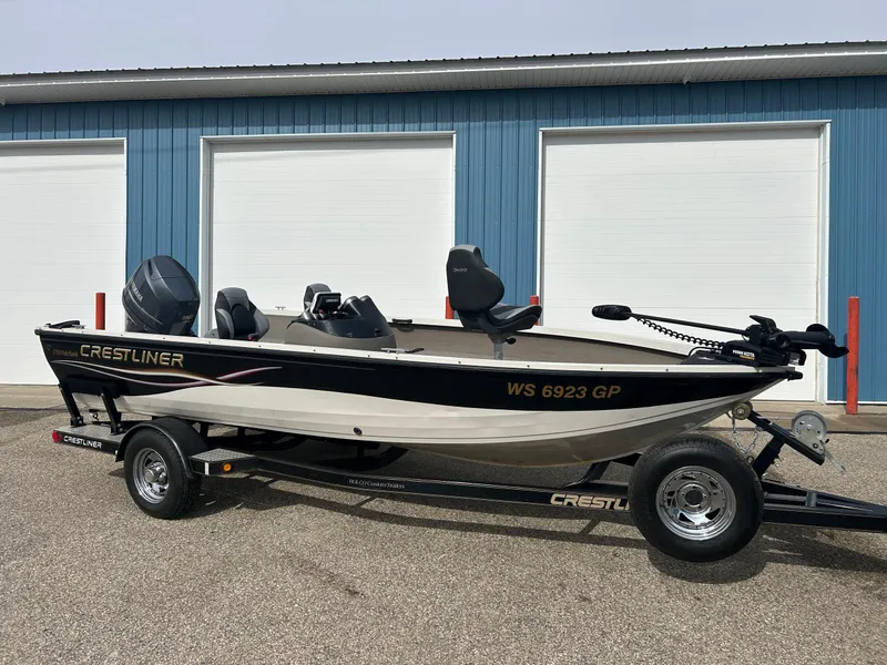 Slide: The Image of 2004 Crestliner 1750 FishHawk SC boat on trailer, parked near blue garage doors. - 2