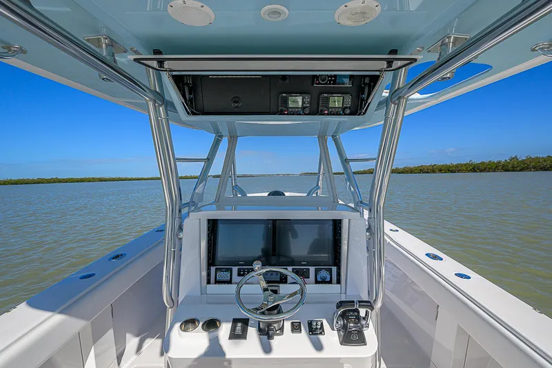 Slide: The Image of 2017 Bahama 41 boat helm with dual screens, steering wheel, and controls on open water. - 28