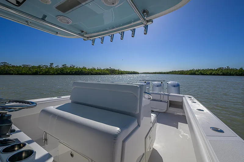 Slide: The Image of 2017 Bahama 41 boat on calm water, clear sky, lush green shoreline. - 30