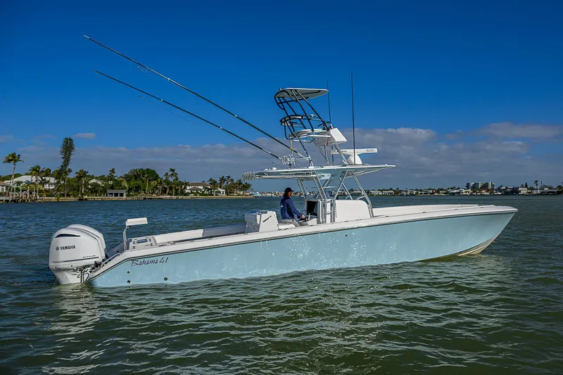 Slide: The Image of 2017 Bahama 41 boat on water, clear sky, palm trees in background. - 34