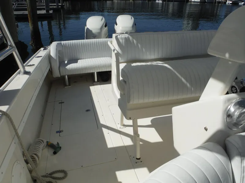 Slide: The Image of 1996 Intrepid 339 Walk Around boat interior with white seating and dual outboard motors. - 33
