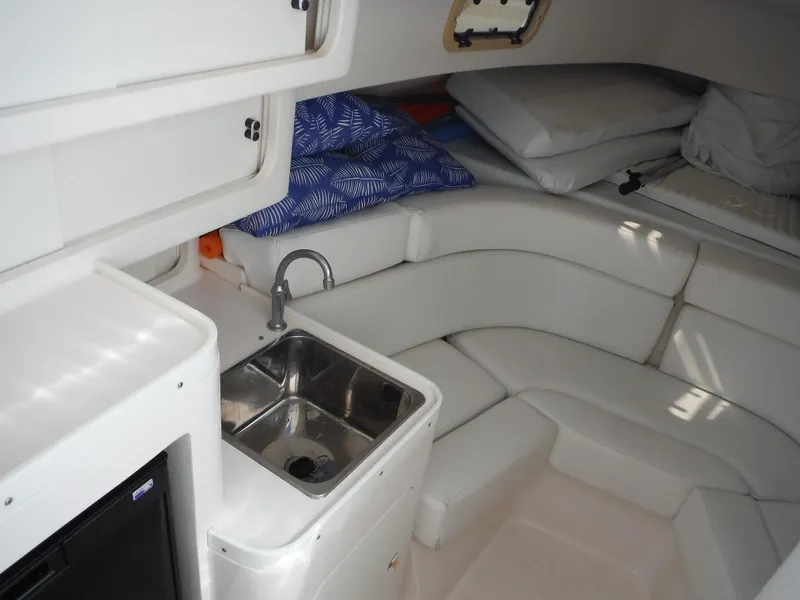 Slide: The Image of 1996 Intrepid 339 Walk Around cabin interior with white seating and small sink. - 44