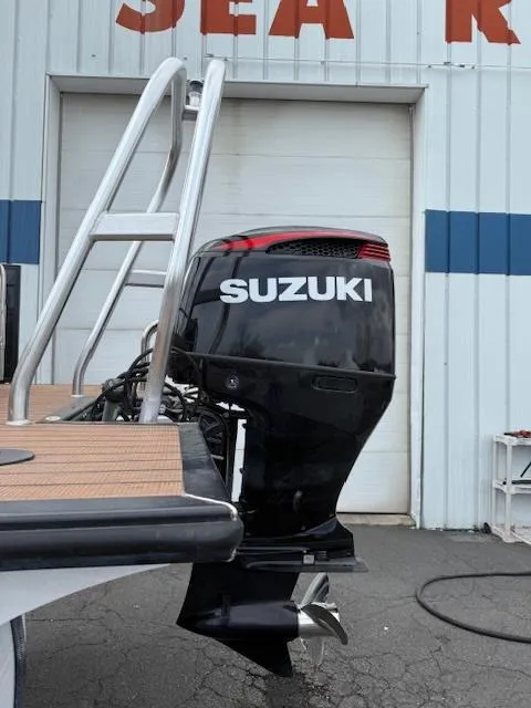 Slide: The Image of 2021 Bentley Pontoons 253 with Suzuki outboard motor, docked near a garage. - 15