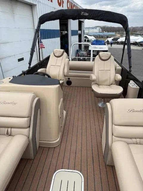 Slide: The Image of 2021 Bentley Pontoons 253 with beige seating and wood-style flooring at a marina. - 6