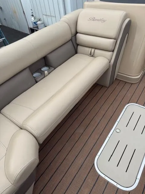 Slide: The Image of 2021 Bentley Pontoons 253 with beige seating and wood-style flooring. - 8