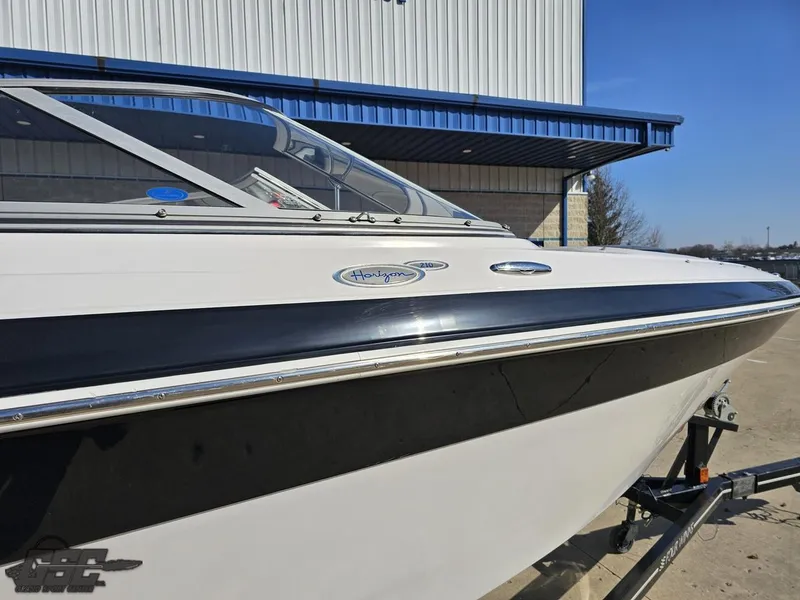 Slide: The Image of 2007 Four Winns 210 Horizon boat, white exterior, parked on a trailer near a building. - 6