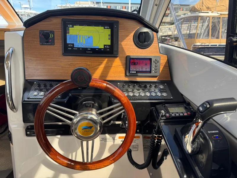 Slide: The Image of 2021 Cutwater C-24 Coupe helm with wooden steering wheel and navigation displays. - 28