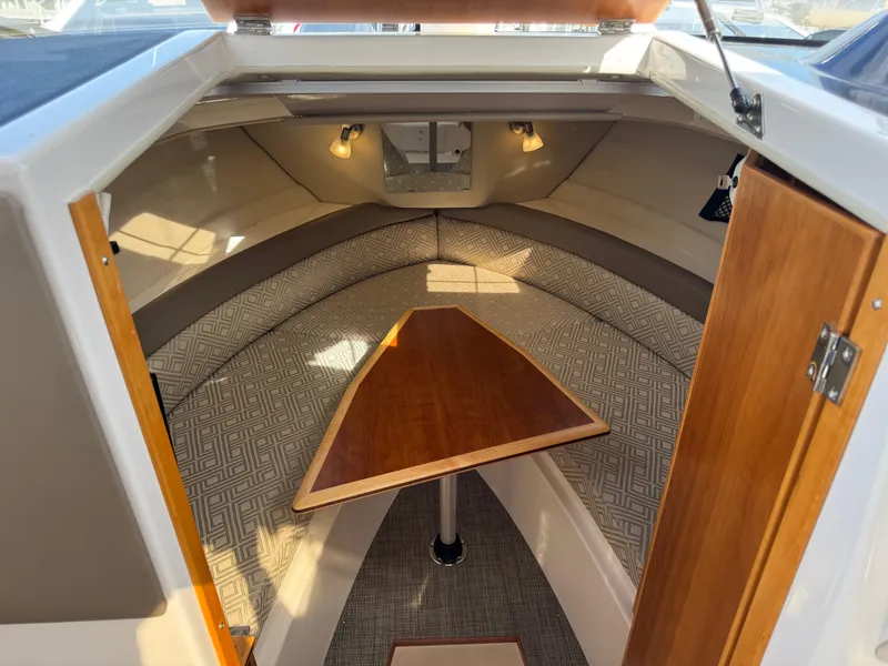 Slide: The Image of 2021 Cutwater C-24 Coupe cabin interior with triangular wooden table and cushioned seating. - 38