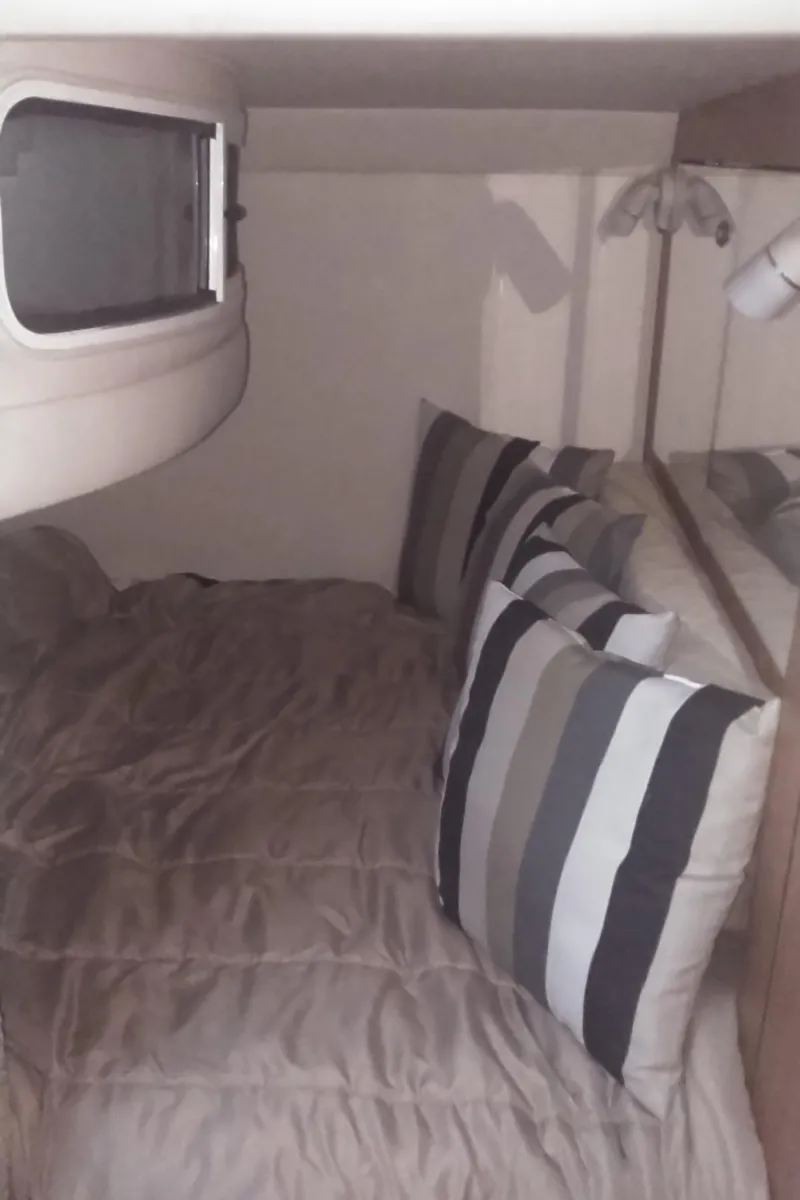 Slide: The Image of 2006 Sea Ray 280 Sundancer cabin interior with bed and striped pillows. - 22