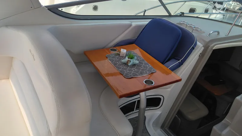 Slide: The Image of 2006 Sea Ray 280 Sundancer interior with seating and wooden table setup. - 25