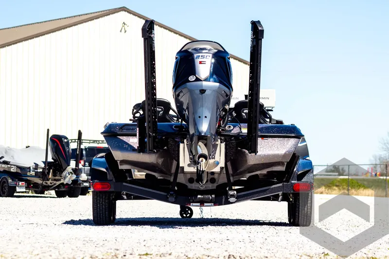 Slide: The Image of 2025 Skeeter FXR 21 Limited boat, rear view, parked on gravel near a building. - 7