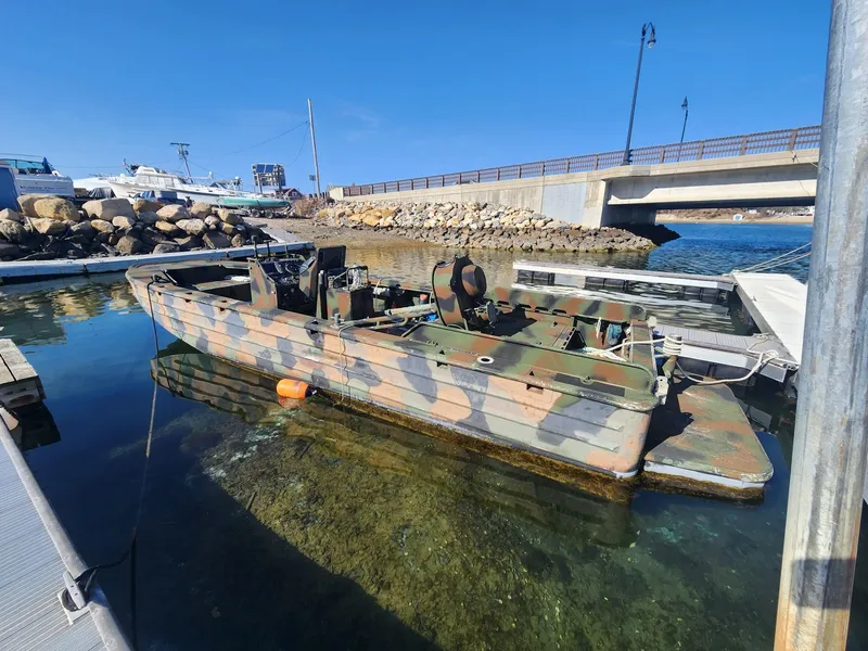 The Image of Camouflaged Recon SWCC Special Operations Vessel docked near a bridge, partially submerged. - 0