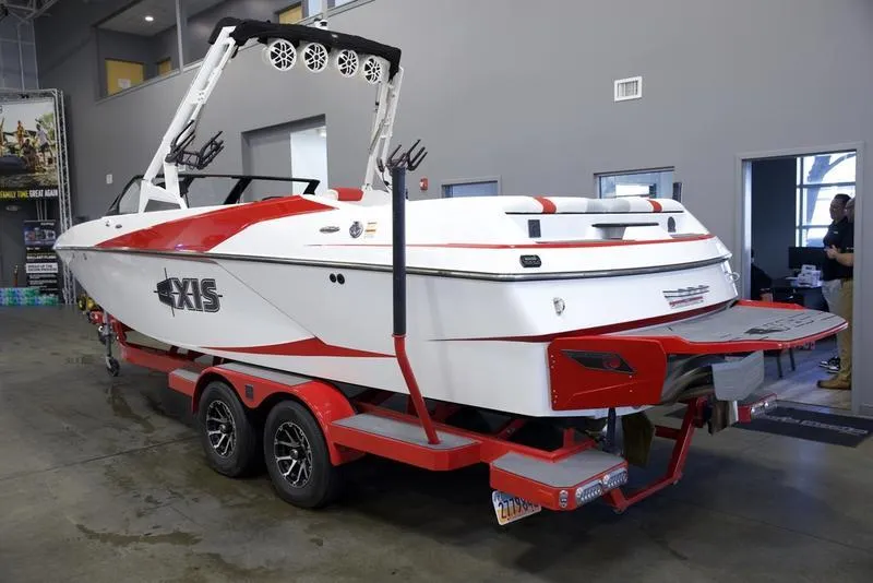Slide: The Image of 2020 Axis A24 boat on trailer in showroom, red and white design. - 2