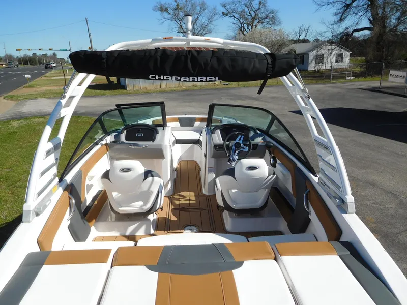 Slide: The Image of 2025 Chaparral 21 SSi boat interior with white and tan seating, parked outdoors. - 5