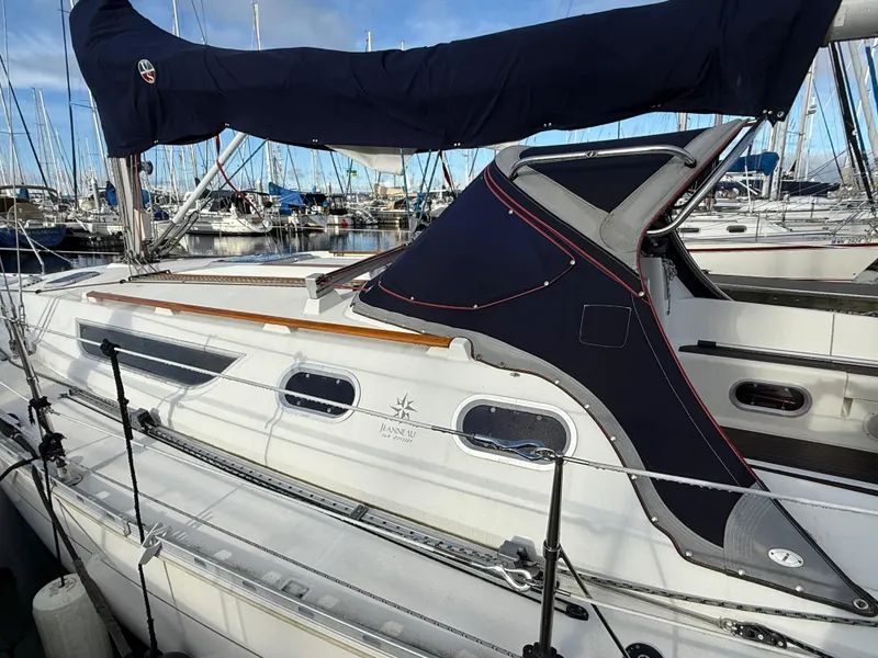 Slide: The Image of 1999 Jeanneau Sun Odyssey 36.2 sailboat docked in marina, featuring sleek design and covered cockpit. - 1