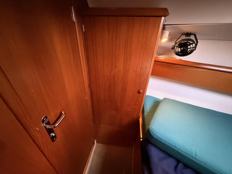 Slide: The Image of Interior of 1999 Jeanneau Sun Odyssey 36.2 yacht, featuring wooden cabinetry and cozy sleeping area. - 19