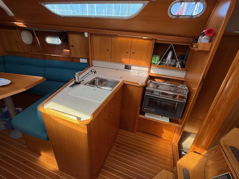 Slide: The Image of Interior of 1999 Jeanneau Sun Odyssey 36.2 sailboat, featuring kitchen and seating area. - 9