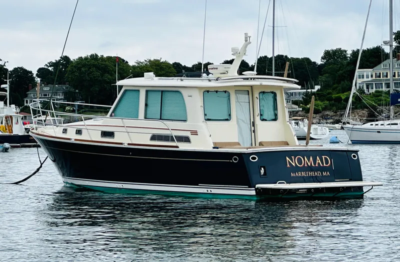 Slide: The Image of 2011 Sabre 40 Sedan boat named "Nomad" docked in a marina. - 1