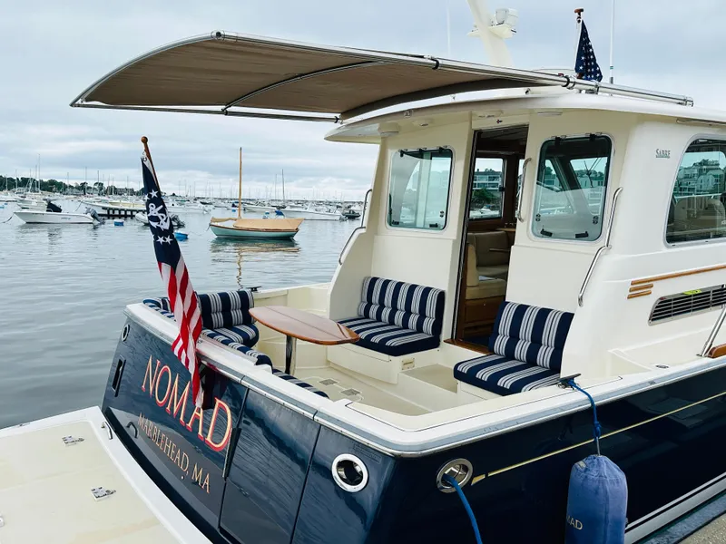 Slide: The Image of 2011 Sabre 40 Sedan yacht docked, featuring striped seating and American flag, in a marina setting. - 11