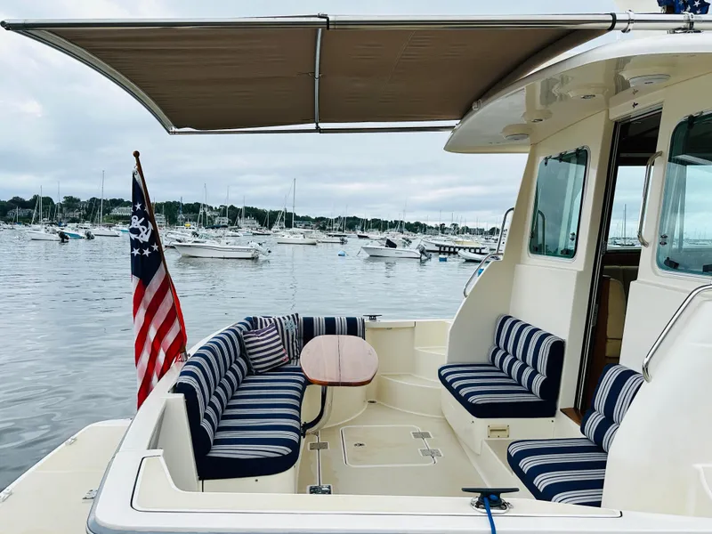 Slide: The Image of 2011 Sabre 40 Sedan boat with striped seating, docked in a marina with an American flag. - 12