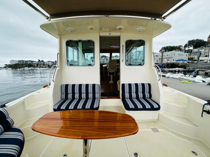 Slide: The Image of 2011 Sabre 40 Sedan yacht with striped seating and wooden table, docked by the waterfront. - 13