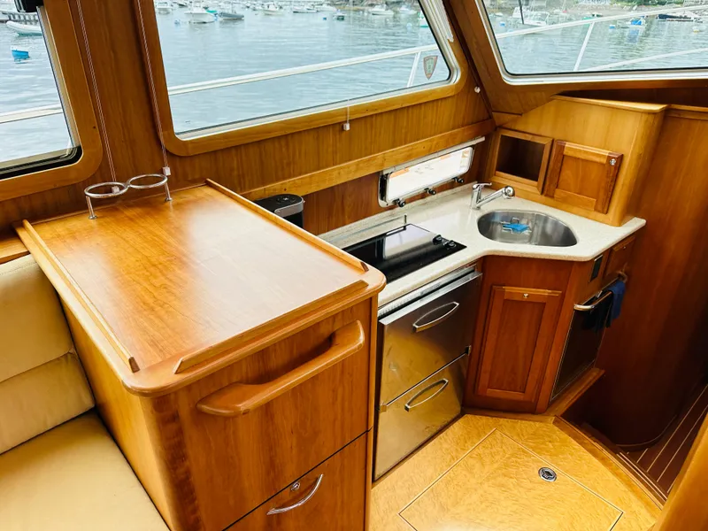 Slide: The Image of 2011 Sabre 40 Sedan interior with wooden cabinetry, compact kitchen, and sink. - 35
