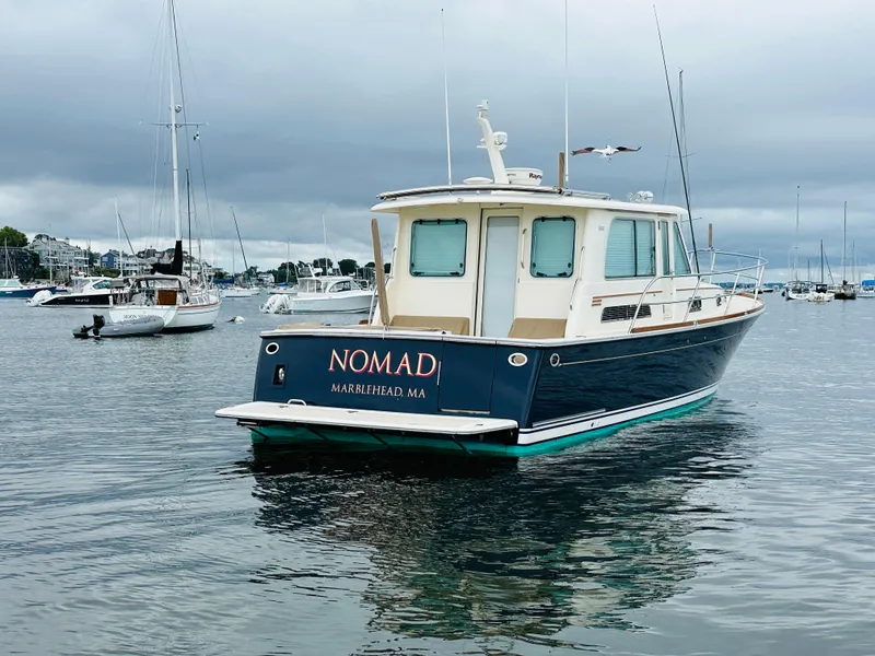 Slide: The Image of 2011 Sabre 40 Sedan boat named "Nomad" on calm water, overcast sky. - 4