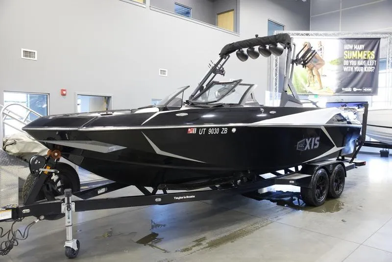 Slide: The Image of 2020 Axis A24 boat on trailer in showroom, black exterior, modern design. - 2