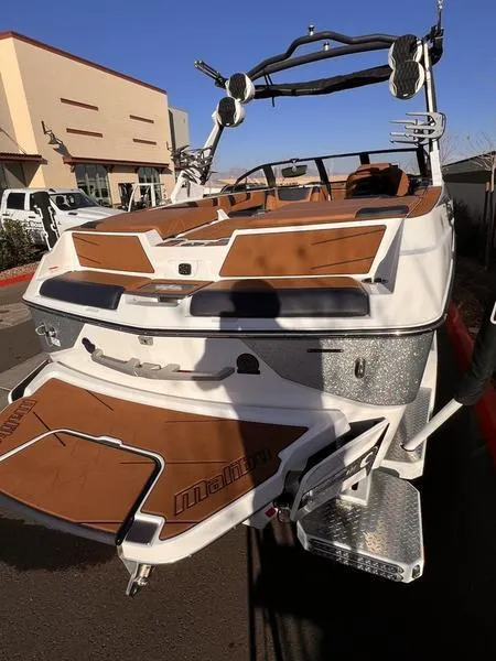 Slide: The Image of 2023 Malibu M220 boat with brown and white detailing, parked outdoors. - 10