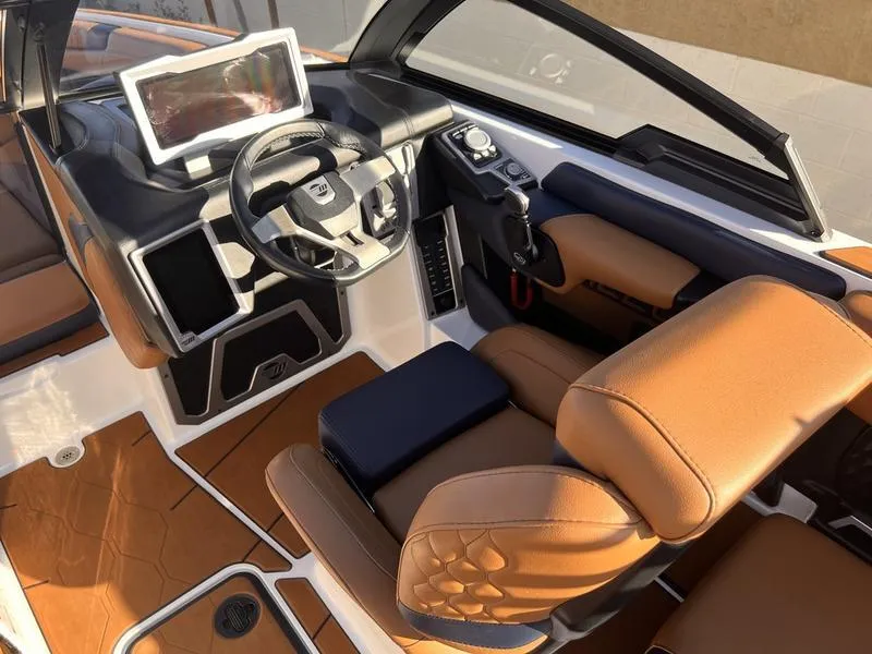 Slide: The Image of 2023 Malibu M220 boat interior with brown leather seats and modern dashboard. - 12
