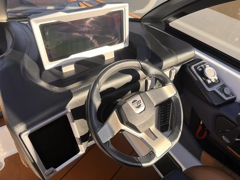 Slide: The Image of 2023 Malibu M220 boat dashboard with steering wheel and touchscreen display. - 13