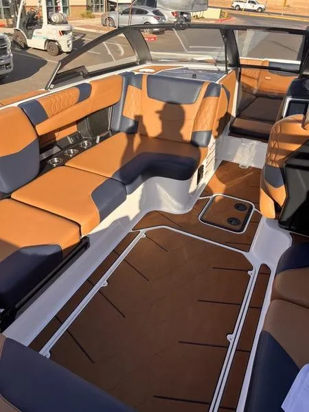 Slide: The Image of 2023 Malibu M220 boat interior with tan and navy seating, spacious layout, and modern design. - 14