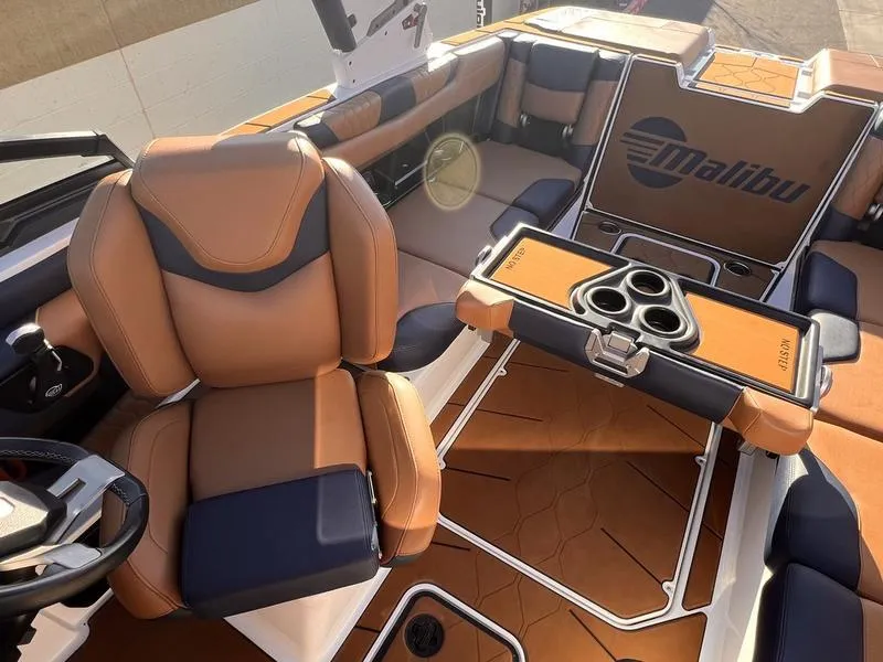 Slide: The Image of 2023 Malibu M220 boat interior with luxurious brown and black seating and cup holders. - 20