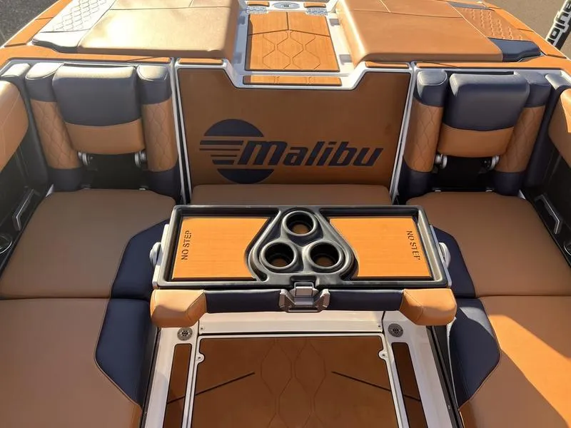 Slide: The Image of 2023 Malibu M220 boat interior with tan and navy seating, featuring cup holders. - 21