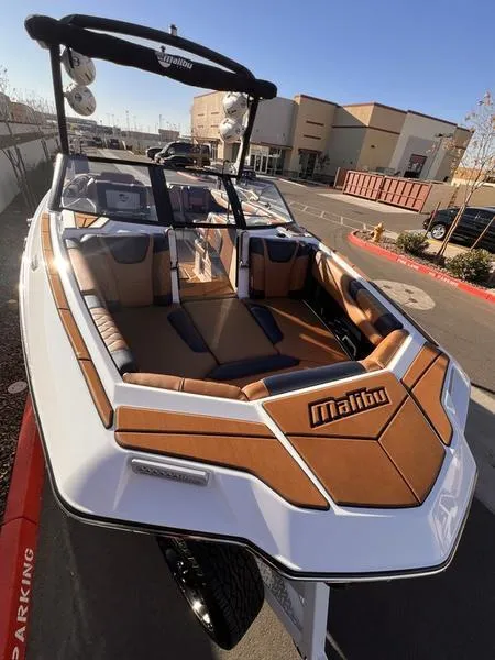 Slide: The Image of 2023 Malibu M220 boat with sleek design and spacious interior, parked outdoors. - 8
