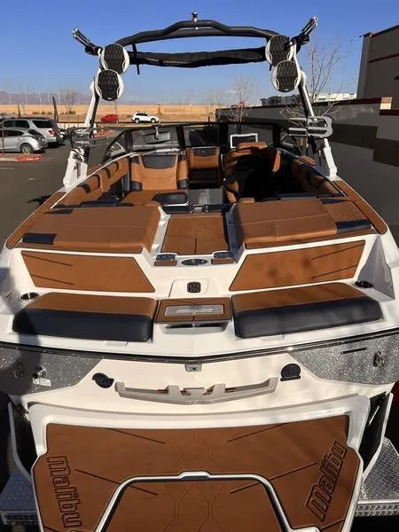Slide: The Image of 2023 Malibu M220 boat with brown and white interior, parked outdoors. - 9