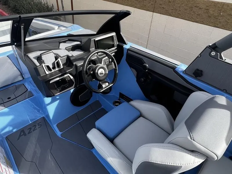 Slide: The Image of Interior of 2025 Axis A225 boat, featuring modern steering and seating in blue and gray. - 12