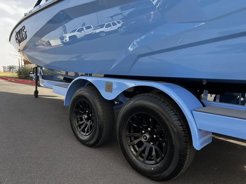 Slide: The Image of 2025 Axis A225 boat on trailer with black wheels, parked on asphalt. - 7