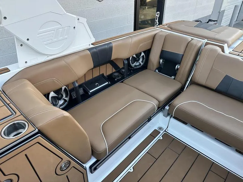 Slide: The Image of 2021 Malibu 24 MXZ boat interior with tan leather seating and cup holders. - 11