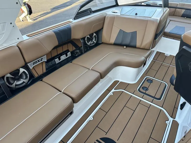 Slide: The Image of 2021 Malibu 24 MXZ boat interior with tan and black seating, modern design, and spacious layout. - 12