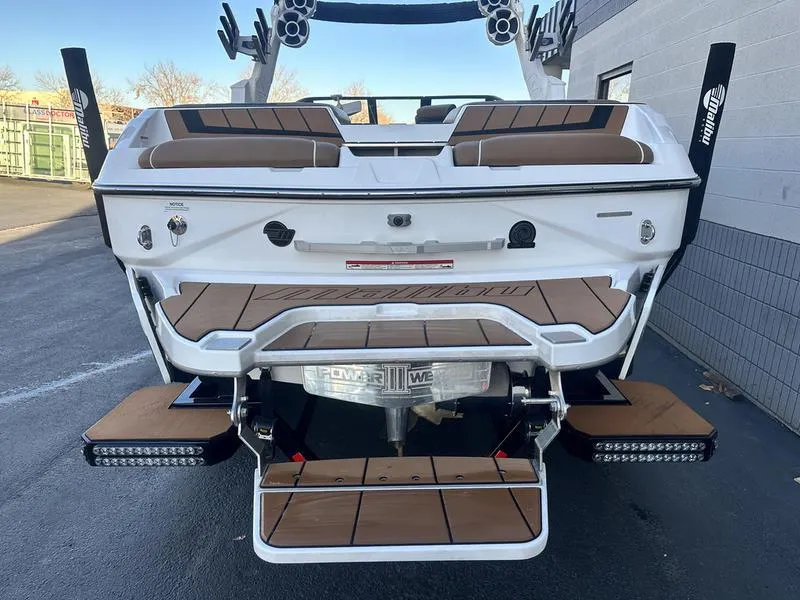 Slide: The Image of 2021 Malibu 24 MXZ boat rear view with teak deck and wakeboard tower. - 7