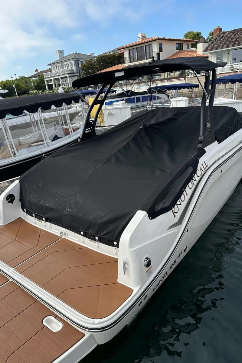 Slide: The Image of 2024 Bayliner DX 2250 boat docked, covered with black tarp, in a marina setting. - 11