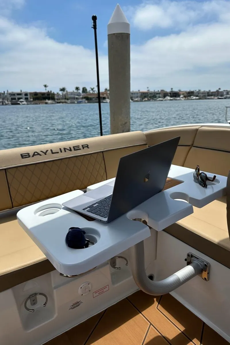 Slide: The Image of 2024 Bayliner DX 2250 boat interior with laptop on table, docked by the water. - 9