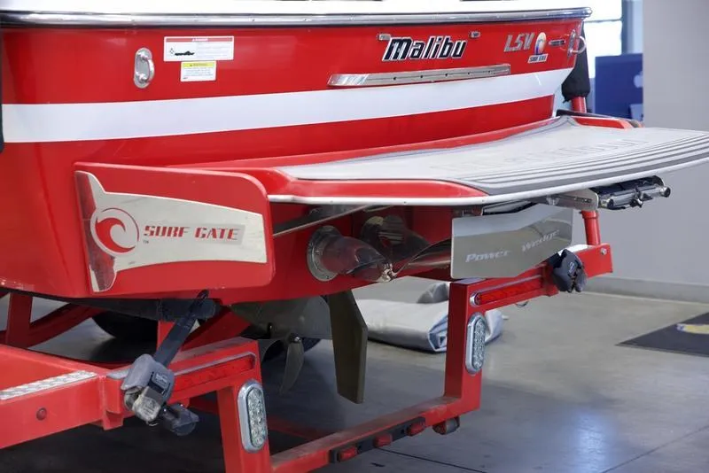 Slide: The Image of 2014 Malibu 247 LSV boat rear view with Surf Gate feature in a garage. - 1