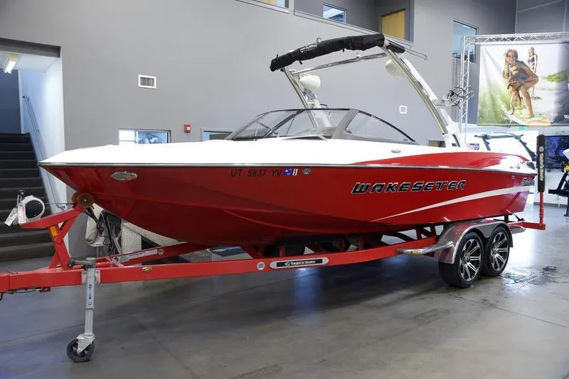 Slide: The Image of 2014 Malibu 247 LSV Wakesetter boat in showroom, red exterior, on trailer. - 18