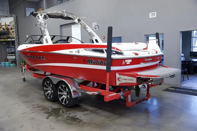 Slide: The Image of 2014 Malibu 247 LSV red boat on trailer in indoor showroom. - 19